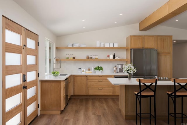 kitchen featuring stainless steel appliances, a kitchen breakfast bar, vaulted ceiling with beams, and light countertops