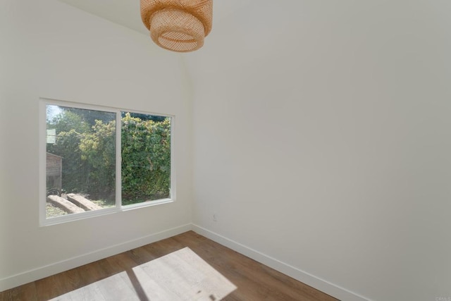 spare room with baseboards and wood finished floors