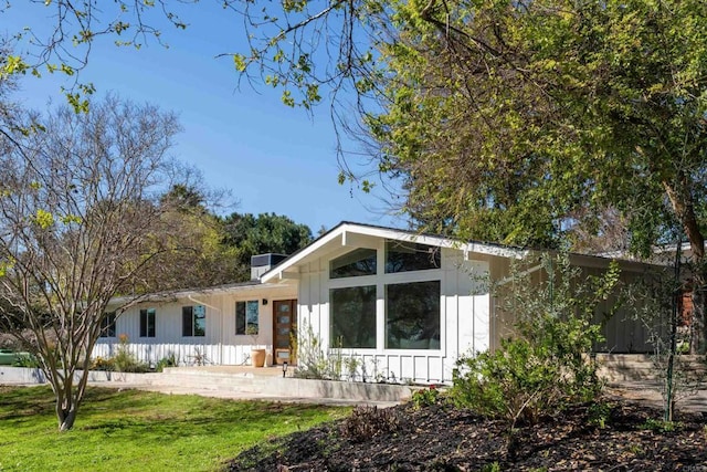 back of house featuring a lawn and board and batten siding