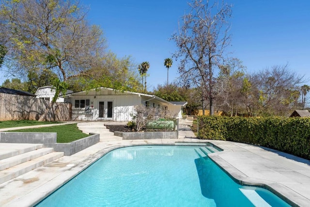 view of swimming pool with a fenced in pool, fence, french doors, and a patio
