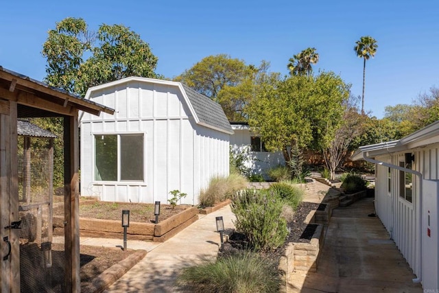 view of home's exterior with an outdoor structure, board and batten siding, a storage shed, and a patio