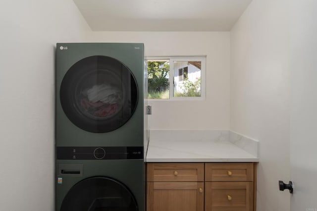 laundry area with stacked washer and clothes dryer and cabinet space