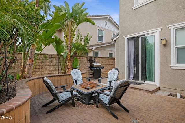 view of patio featuring area for grilling, fence, and an outdoor fire pit