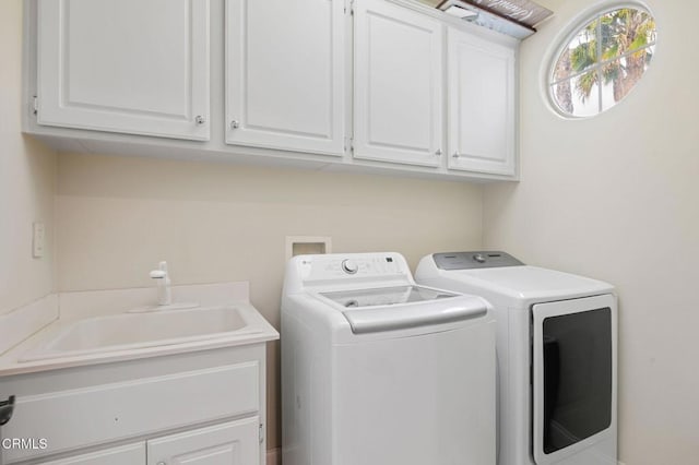 clothes washing area featuring washing machine and clothes dryer, cabinet space, and a sink