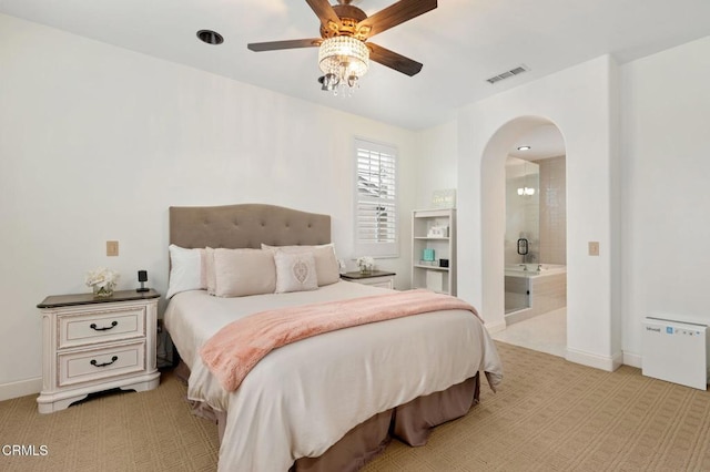 bedroom featuring baseboards, visible vents, arched walkways, and light carpet