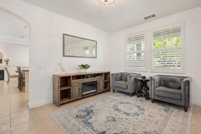 sitting room featuring light tile patterned floors, visible vents, arched walkways, and baseboards