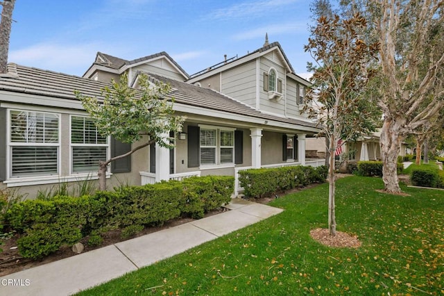 view of front of house with a front yard, a tile roof, and stucco siding