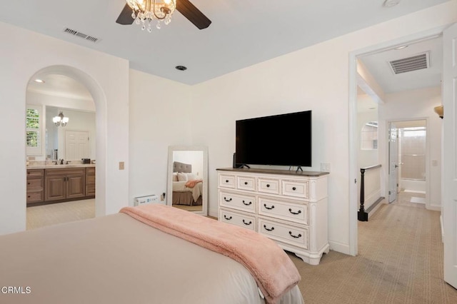 bedroom featuring arched walkways, visible vents, light carpet, and ensuite bathroom