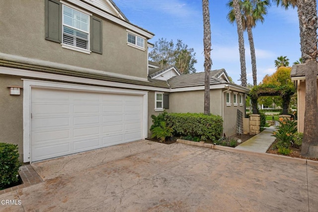 view of home's exterior featuring a tile roof, stucco siding, concrete driveway, and a garage