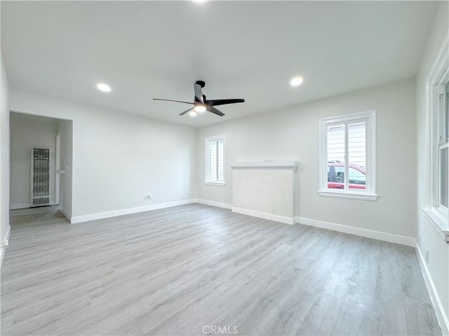 unfurnished living room featuring wood finished floors, plenty of natural light, a ceiling fan, and baseboards