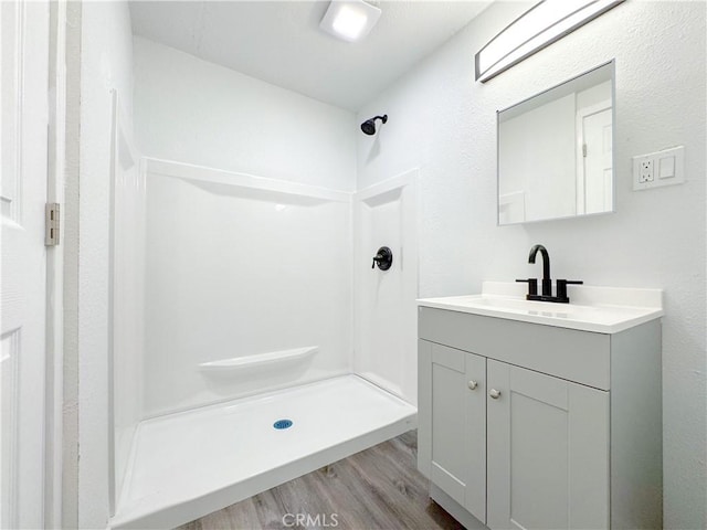 bathroom with vanity, wood finished floors, and walk in shower