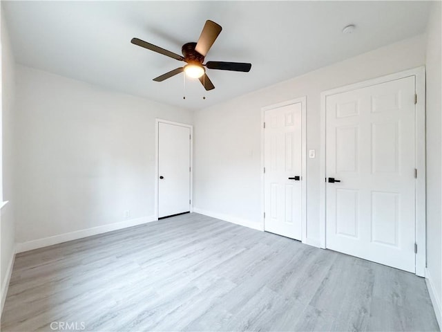 unfurnished bedroom with ceiling fan, baseboards, and light wood-style floors