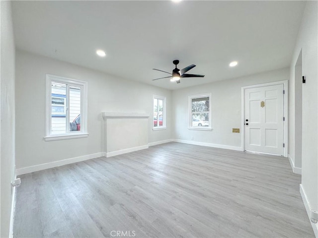 unfurnished living room with light wood-style floors, a ceiling fan, and baseboards