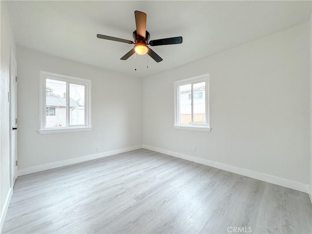 spare room with baseboards, plenty of natural light, and light wood-style flooring