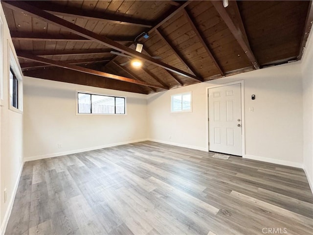 spare room featuring baseboards, wood ceiling, wood finished floors, and vaulted ceiling with beams