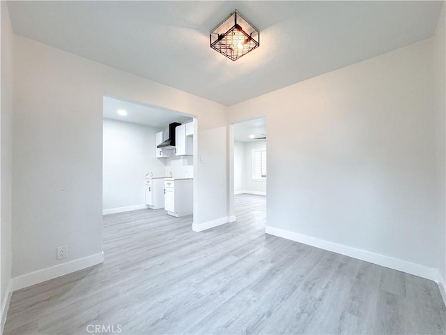 unfurnished living room with light wood-type flooring and baseboards