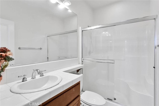 full bathroom with vanity, a shower stall, and toilet