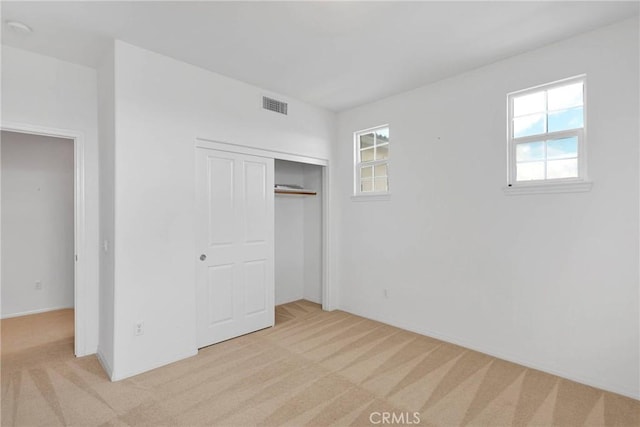 unfurnished bedroom featuring visible vents, a closet, and light carpet