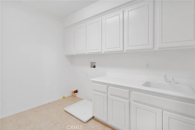 laundry room featuring light floors, baseboards, cabinet space, a sink, and washer hookup