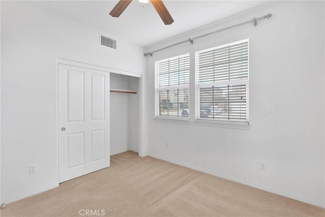 unfurnished bedroom featuring a closet, visible vents, carpet flooring, and a ceiling fan