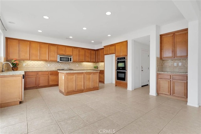 kitchen with stainless steel microwave, brown cabinets, double wall oven, and a sink