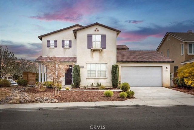 mediterranean / spanish home featuring stucco siding, a tiled roof, an attached garage, and concrete driveway