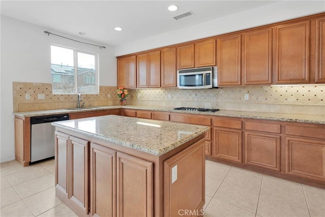 kitchen with visible vents, a kitchen island, a sink, appliances with stainless steel finishes, and brown cabinets