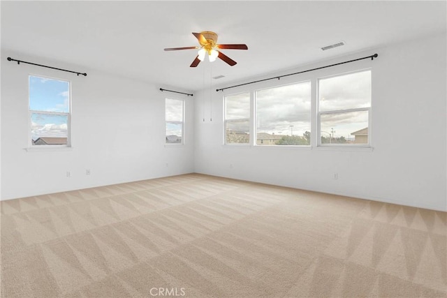 carpeted spare room with visible vents and ceiling fan