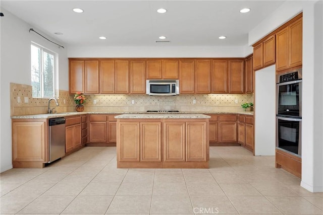 kitchen featuring a sink, appliances with stainless steel finishes, a center island, and brown cabinetry