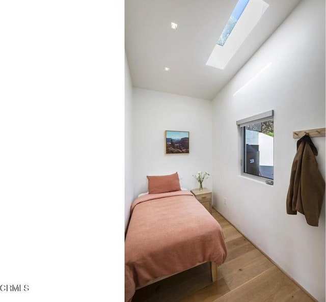 bedroom featuring a skylight and light wood finished floors