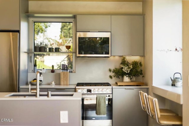 kitchen featuring stainless steel appliances, modern cabinets, gray cabinets, and light countertops