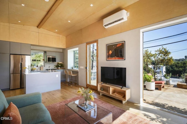 living room featuring lofted ceiling with beams, a wall mounted air conditioner, and light wood-type flooring