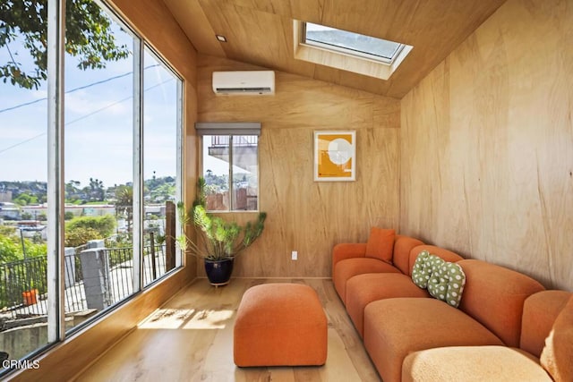 living room with vaulted ceiling with skylight, wood finished floors, and a wall mounted air conditioner