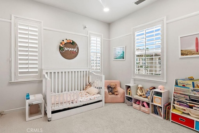 carpeted bedroom featuring visible vents and a crib