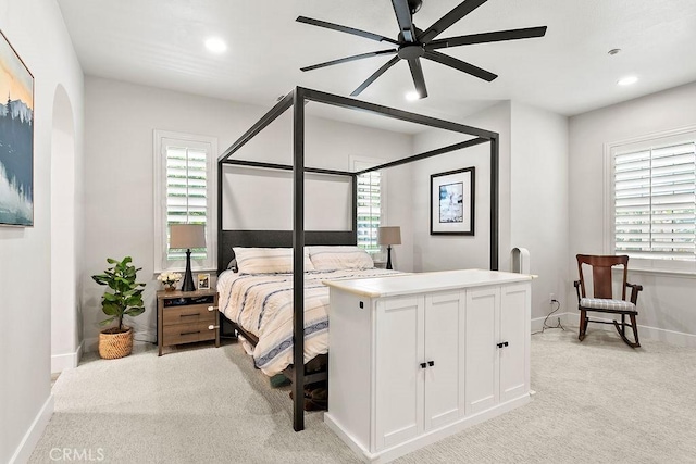 bedroom featuring recessed lighting, baseboards, light carpet, and arched walkways