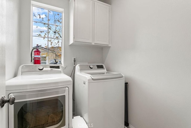 clothes washing area featuring washing machine and dryer, plenty of natural light, and cabinet space