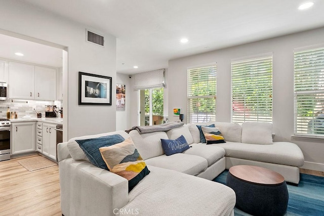 living area with a wealth of natural light, visible vents, light wood-style flooring, and recessed lighting