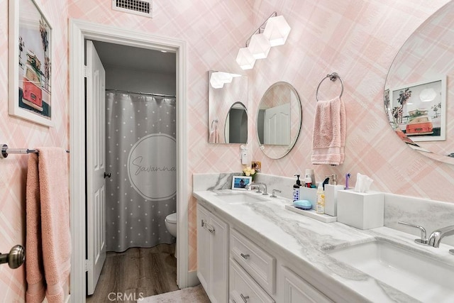 full bath with a sink, visible vents, and wallpapered walls