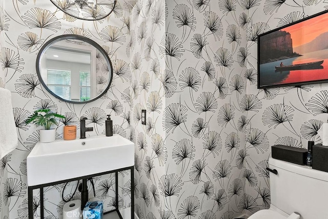 half bath with wallpapered walls and a sink