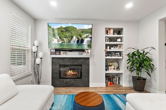 living room with built in features, wood finished floors, baseboards, recessed lighting, and a tile fireplace