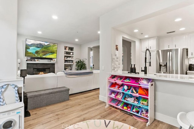 interior space with recessed lighting, visible vents, light wood-style flooring, and a glass covered fireplace