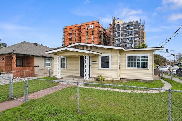 bungalow with a front lawn, a gate, and a fenced front yard