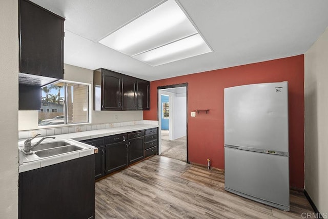 kitchen featuring a sink, light wood finished floors, and freestanding refrigerator