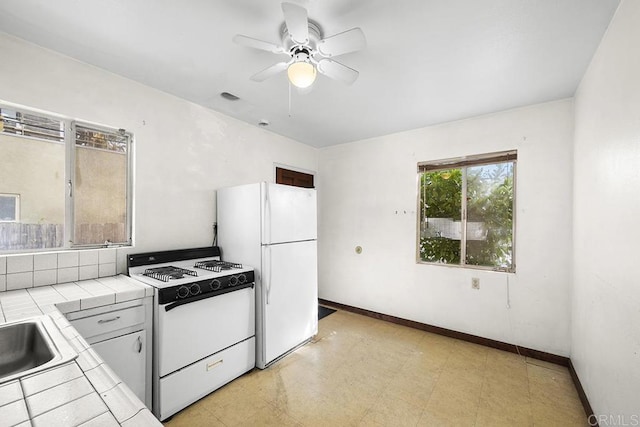 kitchen featuring white appliances, tile counters, baseboards, light floors, and ceiling fan