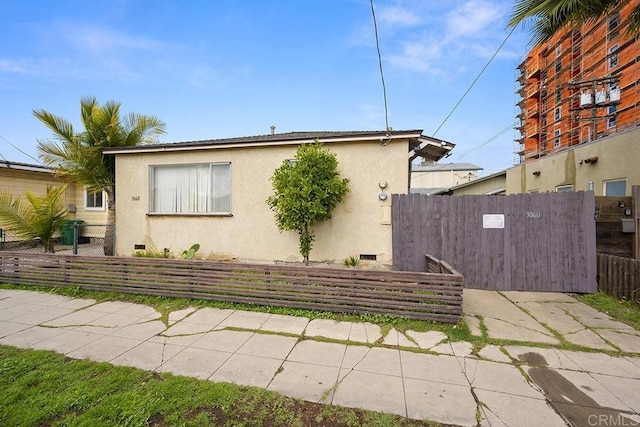 view of side of home featuring a gate, stucco siding, and fence