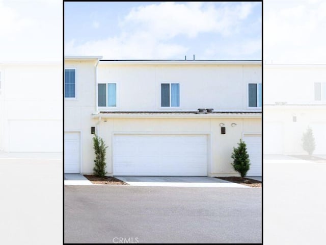 view of property featuring a garage, driveway, and stucco siding