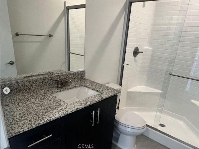 bathroom with vanity, tile patterned floors, toilet, and a stall shower