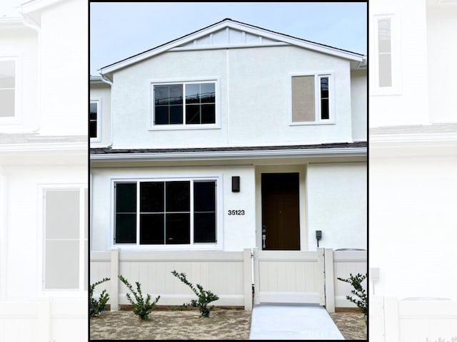 view of front of property with stucco siding, fence, and a gate