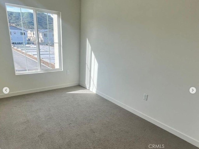 carpeted spare room featuring baseboards