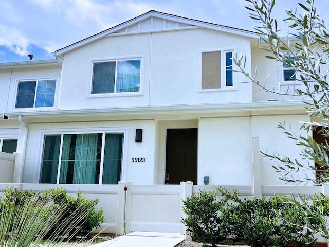 view of property with a gate, a fenced front yard, and stucco siding